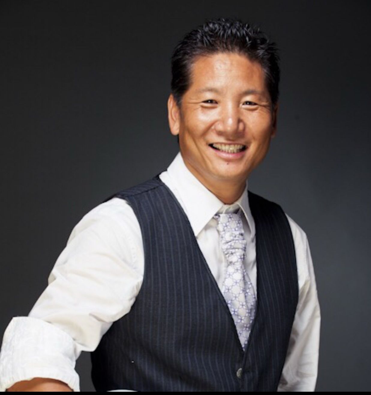 A man wearing a vest and tie smiles for the camera