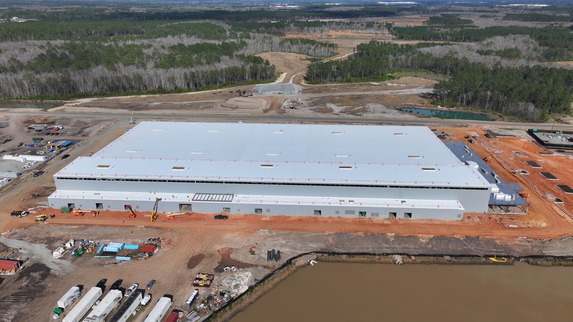 An aerial view of a large building under construction next to a body of water.