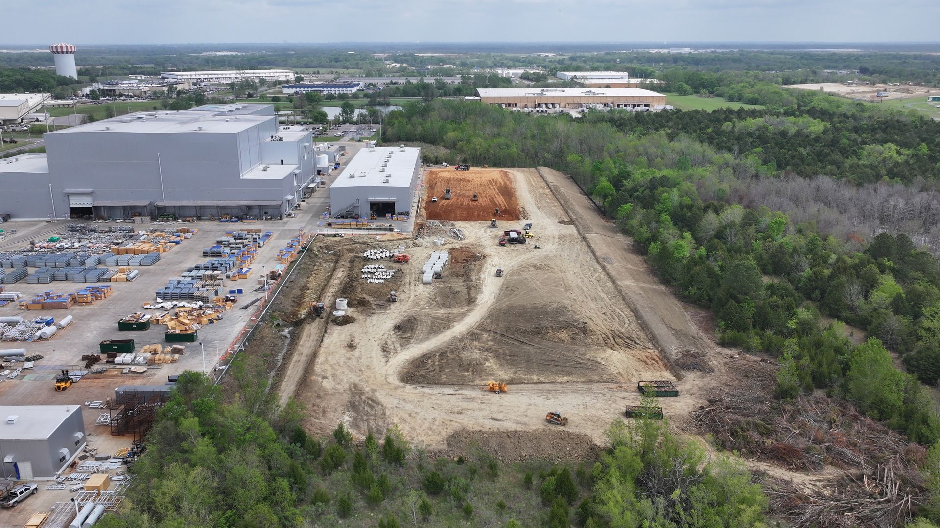 An aerial view of a large industrial area surrounded by trees and buildings.