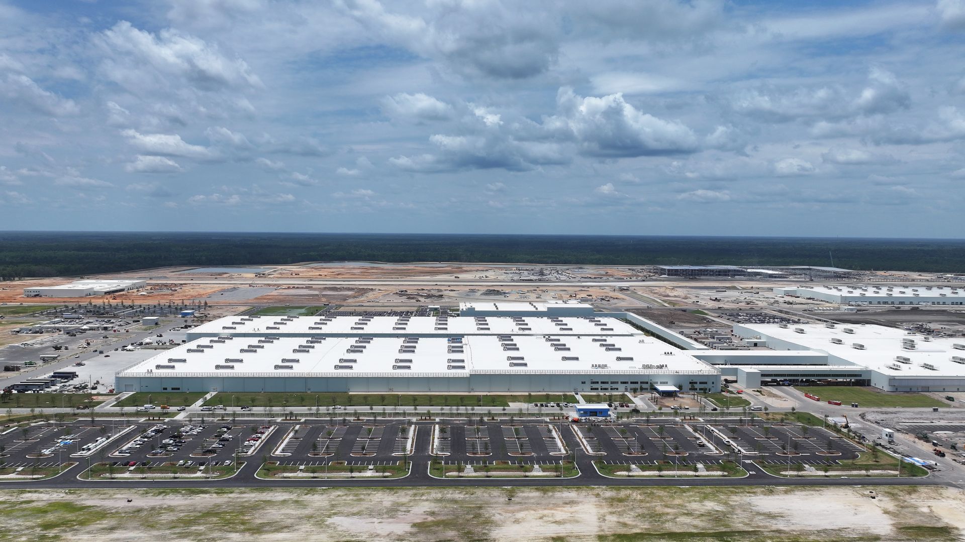 An aerial view of a large white building with a parking lot in front of it.