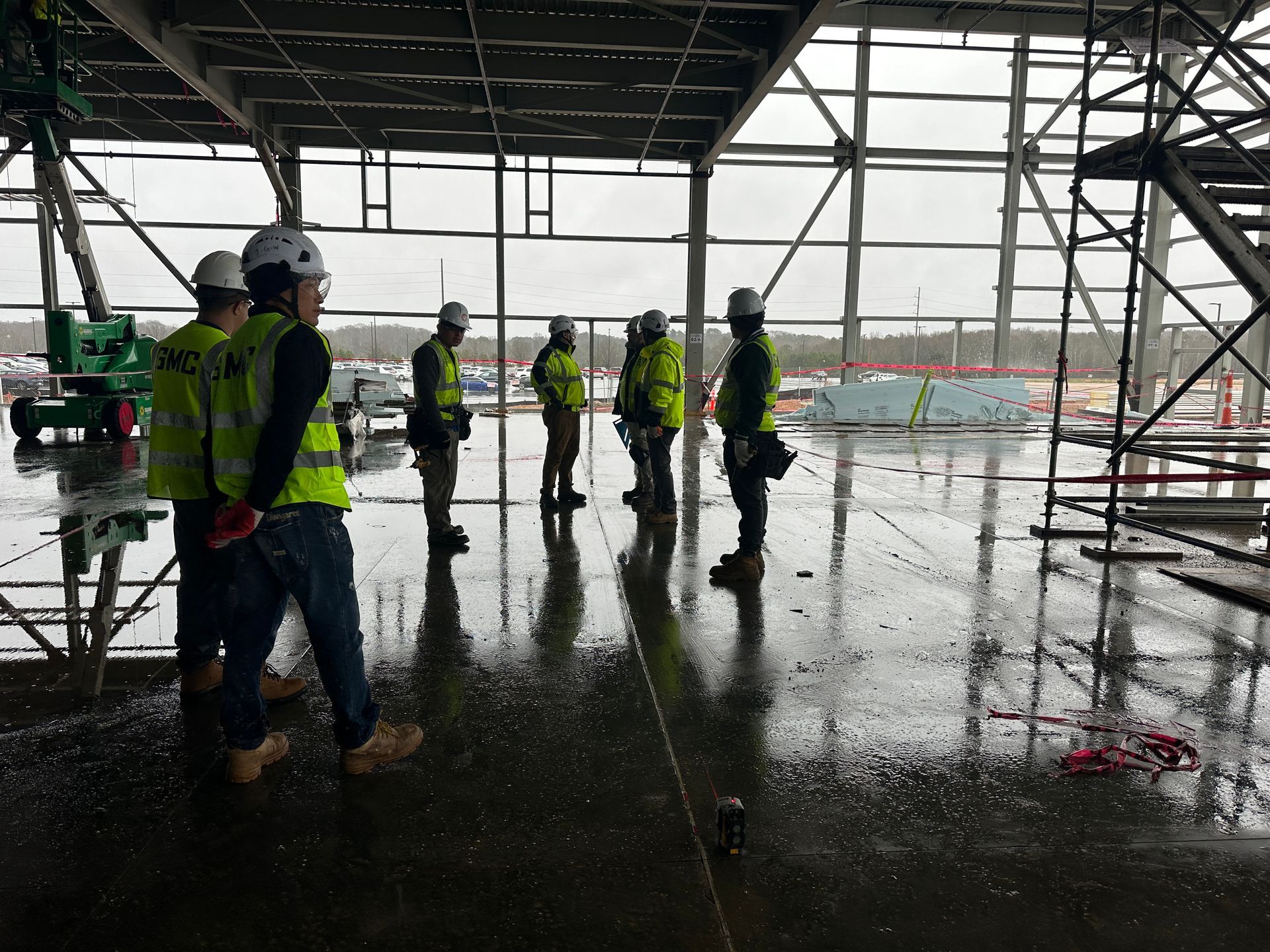 A group of construction workers are standing in a building in the rain.