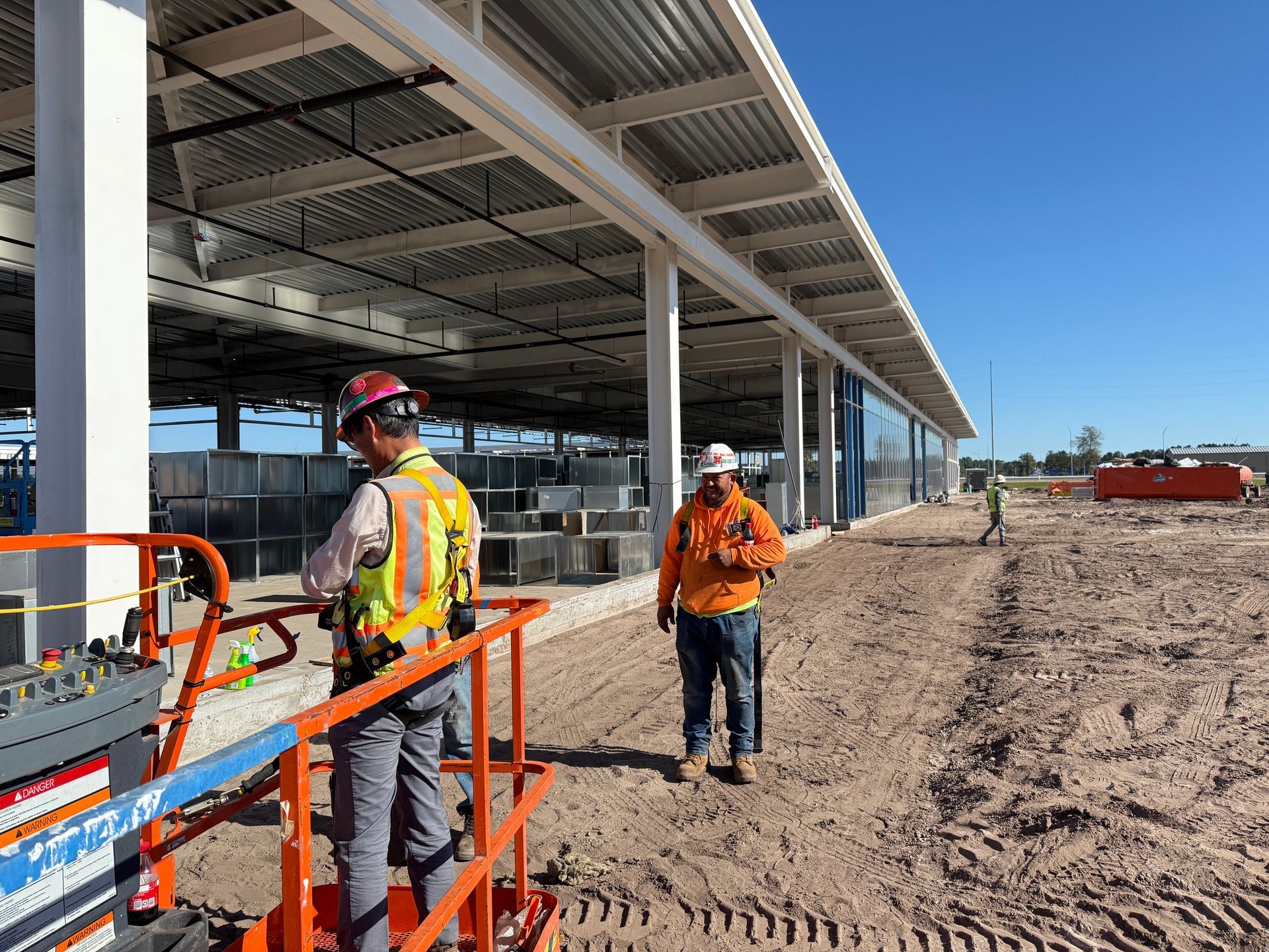 Two construction workers are standing in front of a building under construction.