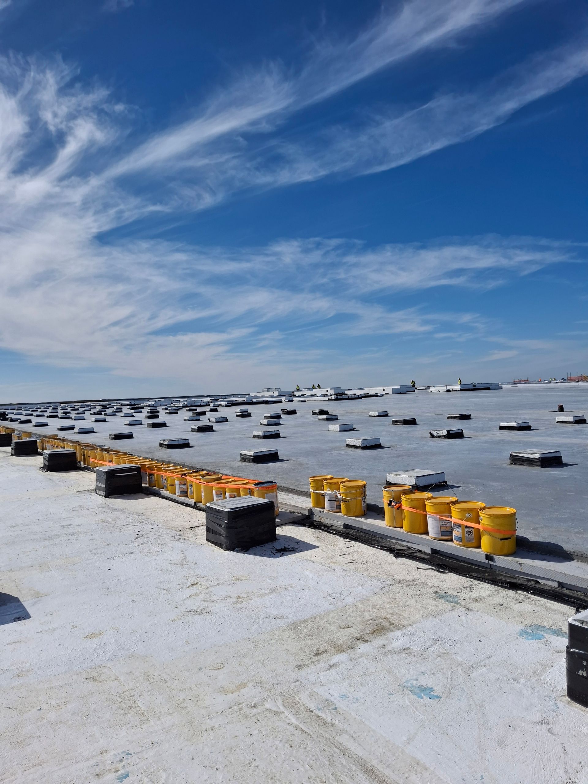 A row of yellow barrels are lined up on a snowy roof