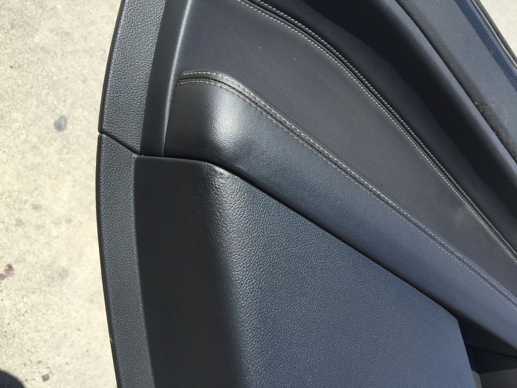Close-up of a black leather car seat with textured panel and stitching