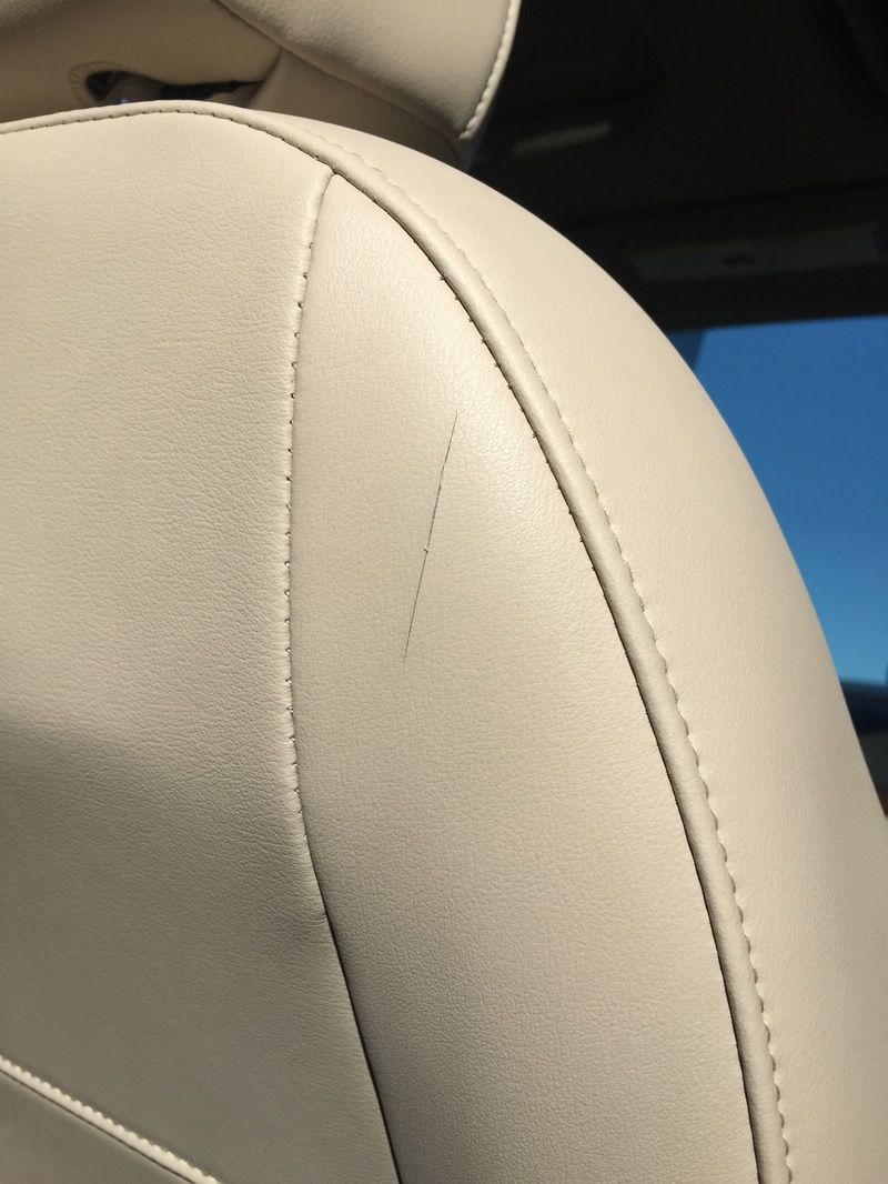 Close-up of a beige leather car seat with stitched seams and headrest edge