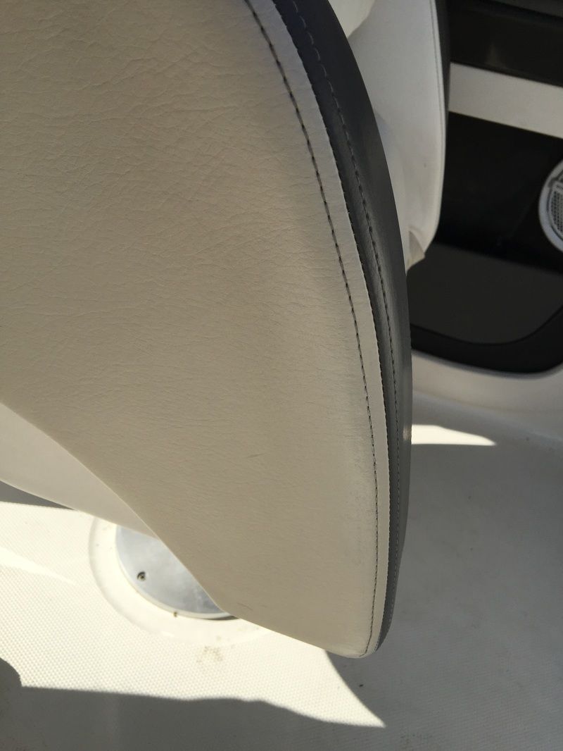 Close-up of a beige car seat with black trim and a white patterned surface below