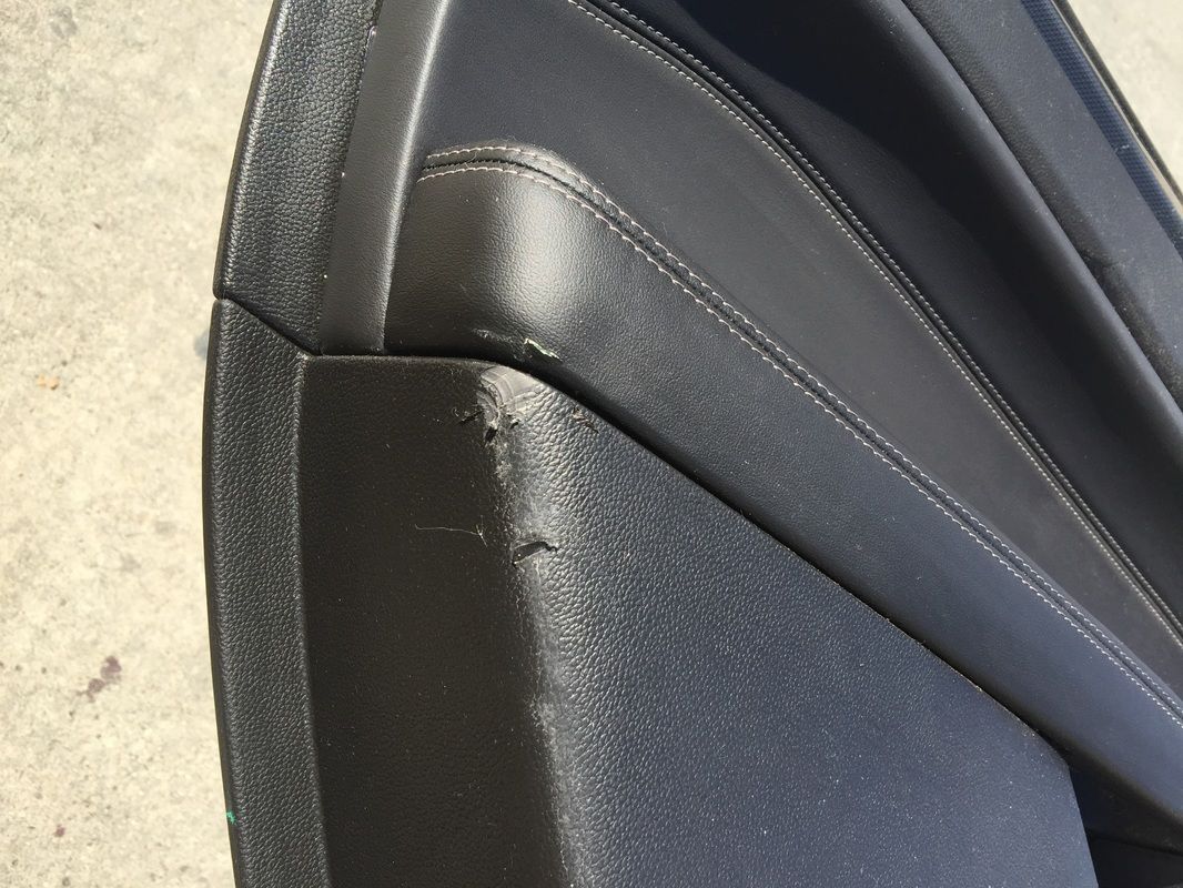 Close-up of a black car seat with a worn, scuffed side panel