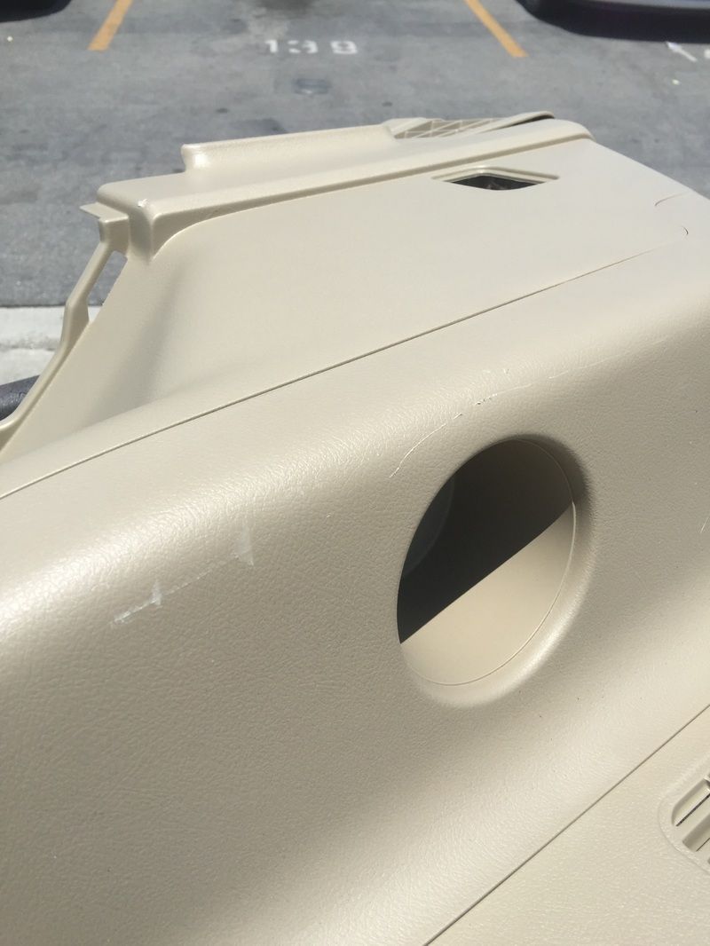 Beige vehicle interior panel with a round cutout, parked in a lot.