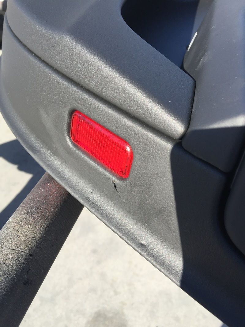 Close-up of a black car door with a red reflector near the bottom edge
