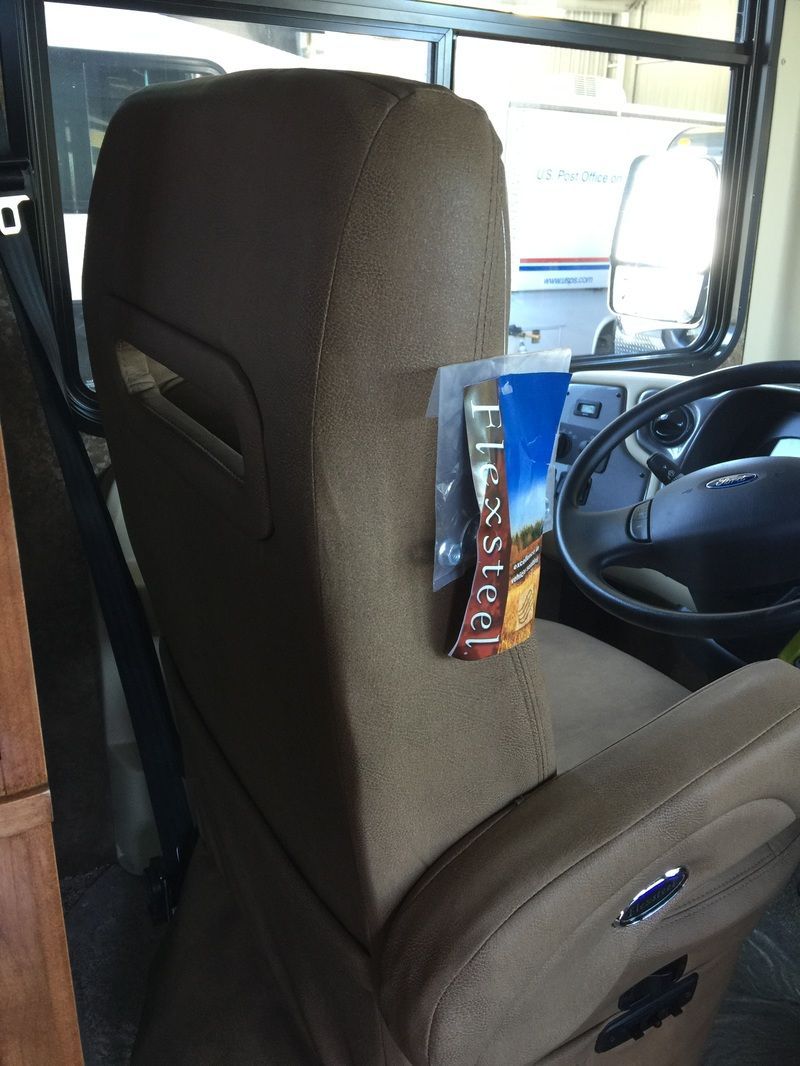 Brown seat in a vehicle interior with a blue cup holder and steering wheel visible.