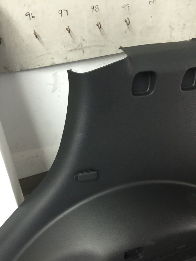 Black plastic car seat backrest beside a wall with handwritten numbers and a small sticker.