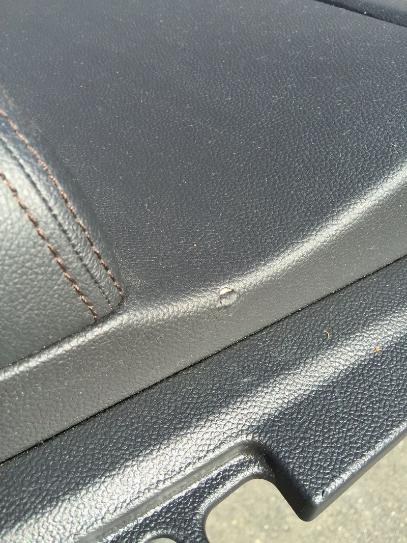 Close-up of a black textured seat seam and molded plastic trim inside a vehicle.