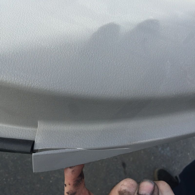 Close-up of a cracked white car bumper with a hand pointing at the damage