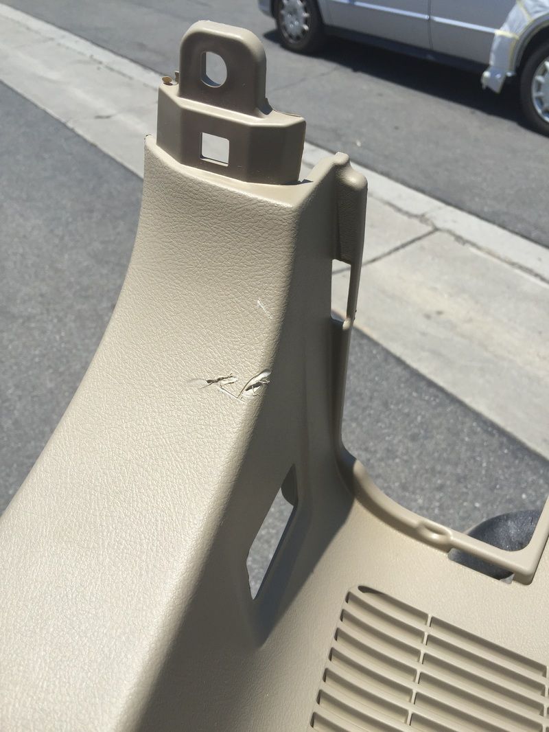 Tan plastic barrier on a sidewalk beside a curb and parked car