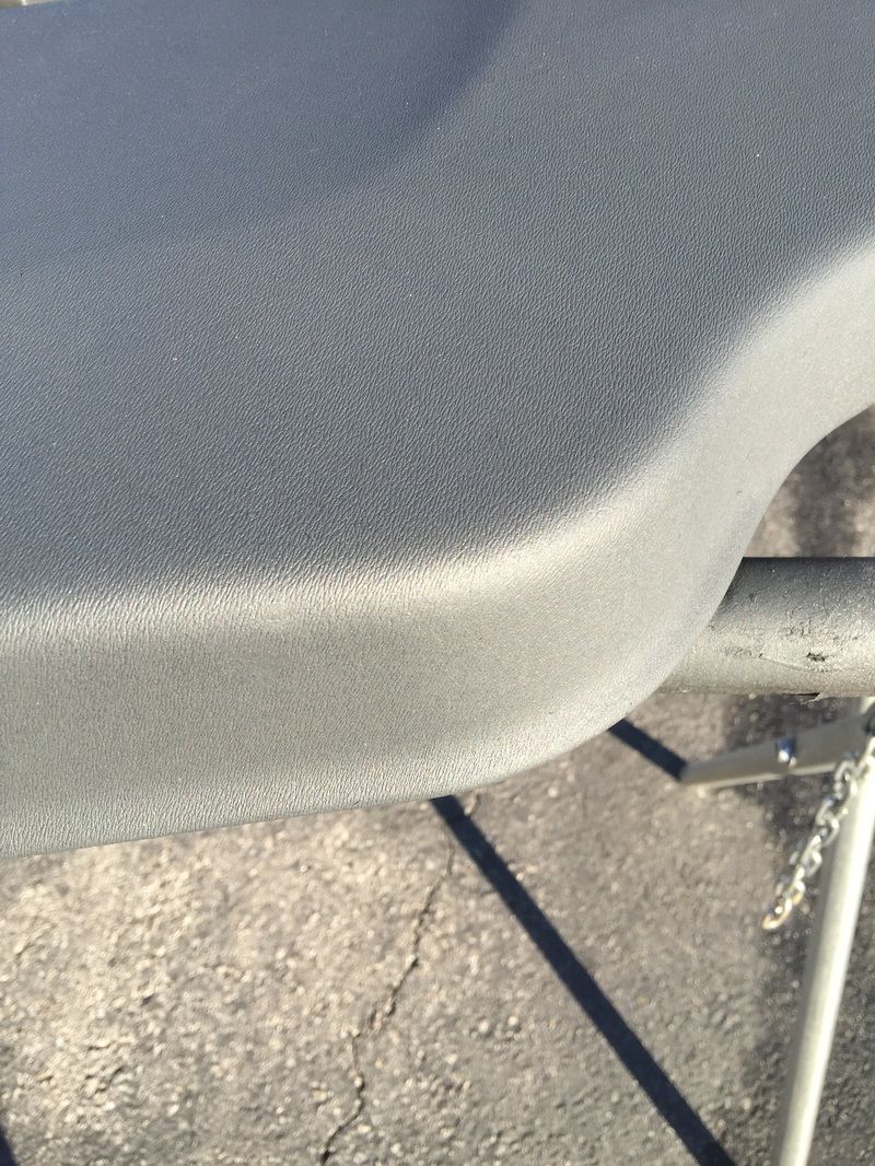 Close-up of a gray textured chair seat and metal frame on a concrete floor