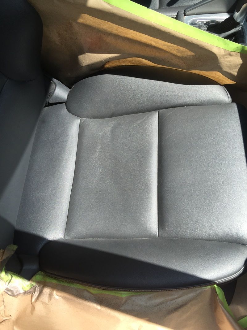 Gray car seat with a brown blanket draped across the top and green straps visible at the sides.