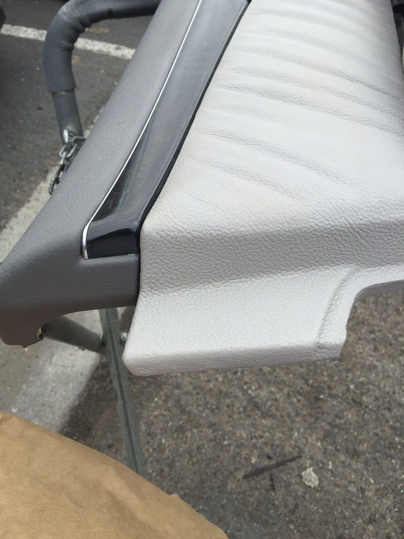 Close-up of a gray upholstered car seat with a torn foam edge and black trim.
