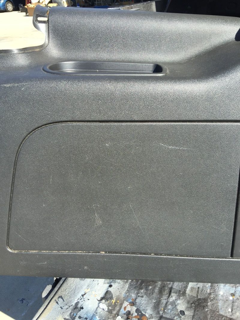 Close-up of a black textured plastic panel with a recessed handle slot.