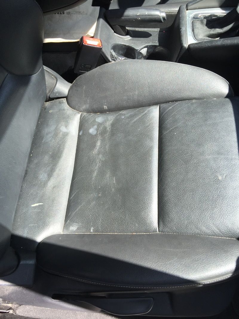 Gray car seat with visible wear and a raised armrest in a vehicle interior
