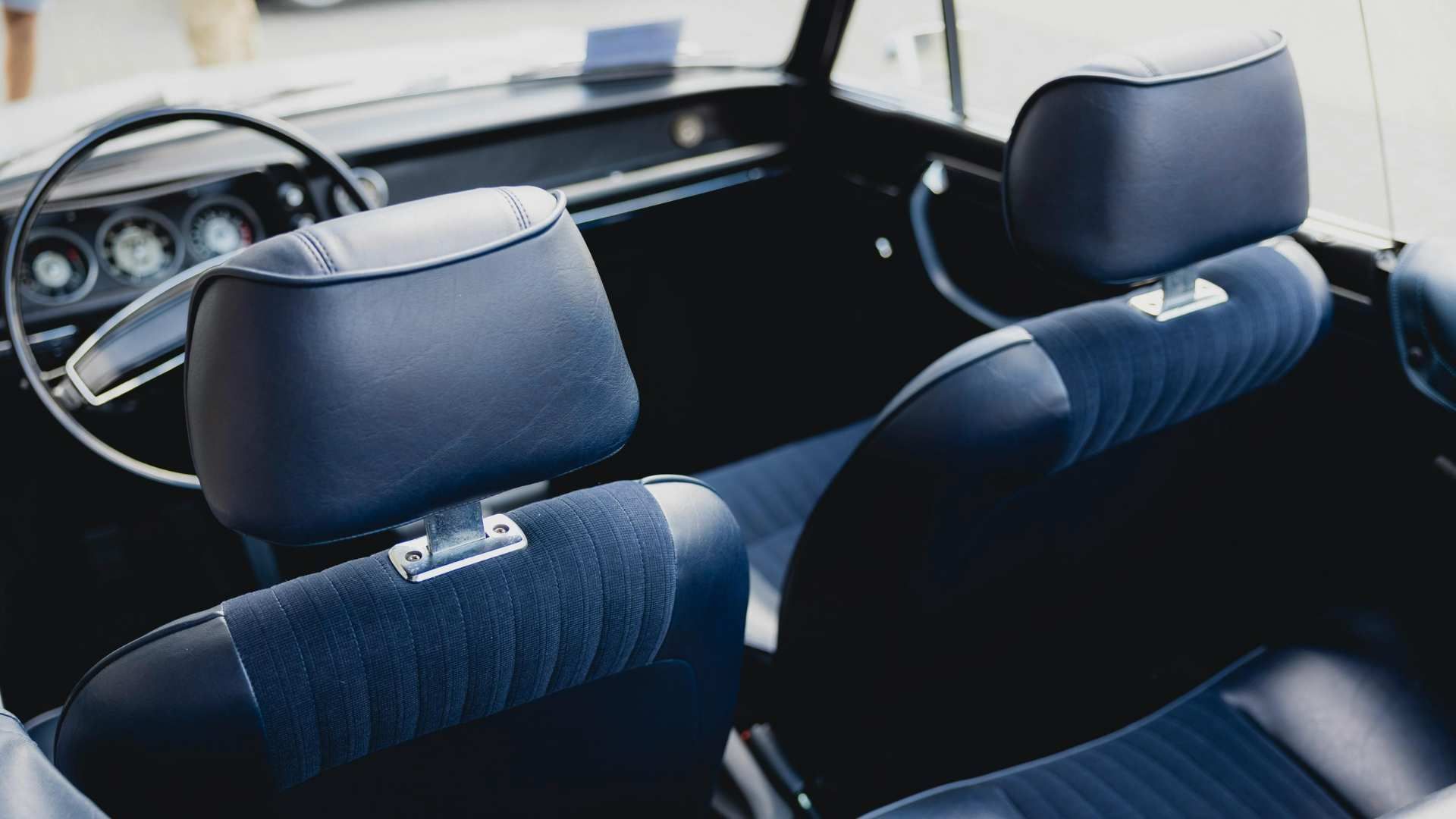 Rear view of a car interior with two black front seats and a steering wheel visible through the windshield