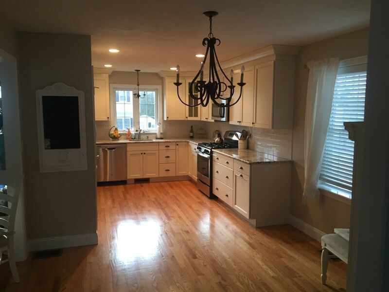 Kitchen with wood floors, light cabinets, stainless steel appliances, and a chandelier.