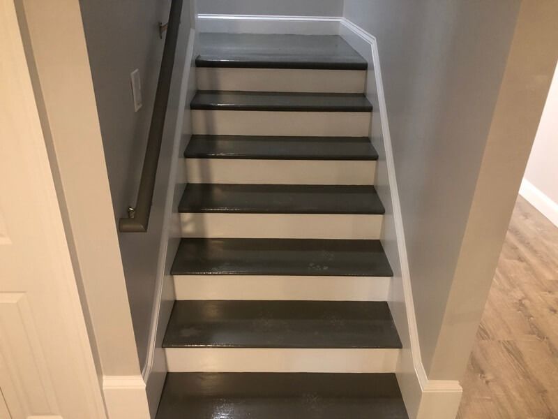 Gray painted wooden stairs with white risers and baseboards.