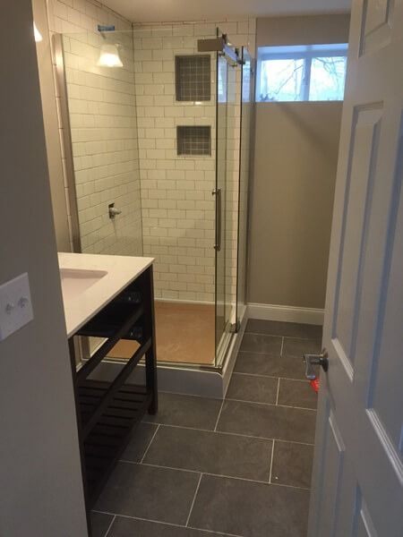 Bathroom with tile floor, glass shower, white vanity, and gray walls.
