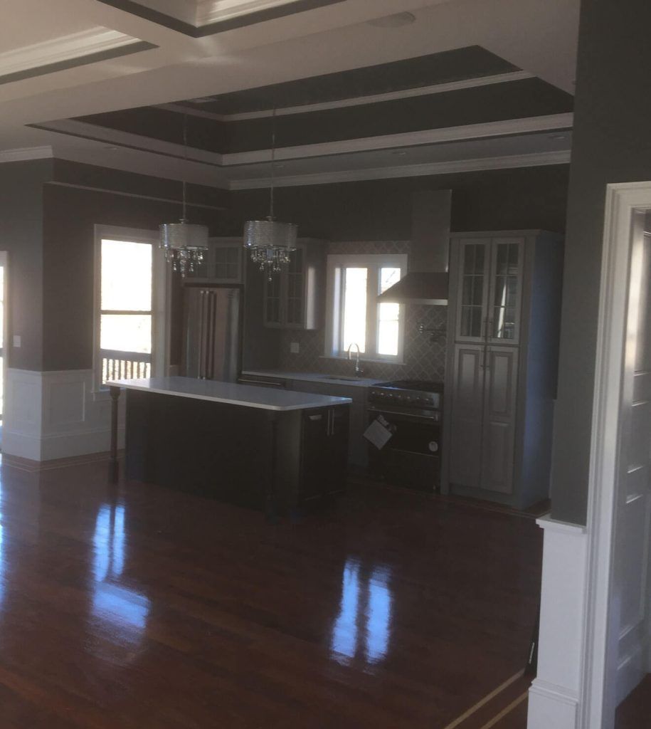 Kitchen with dark gray walls, white trim, and hardwood floors. Island, cabinets, and appliances are visible.