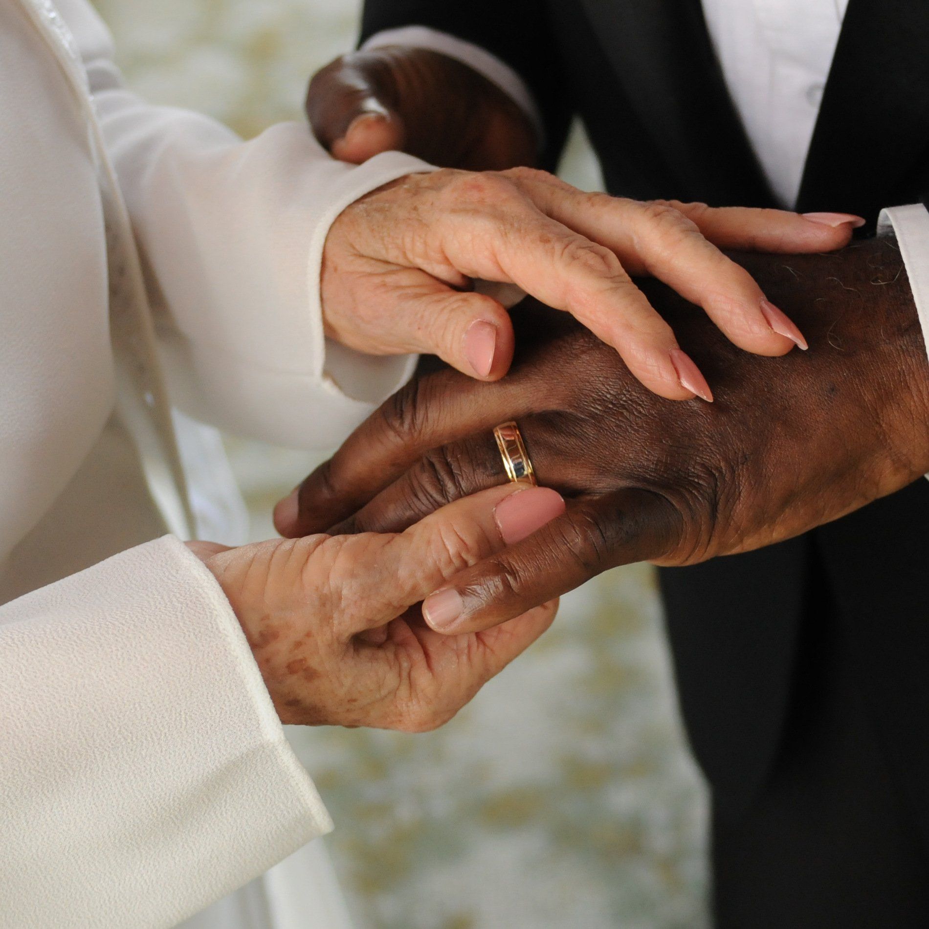 A woman putting a wedding ring on a man 's finger