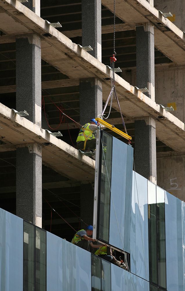 Una grúa está levantando una ventana en un edificio en construcción.