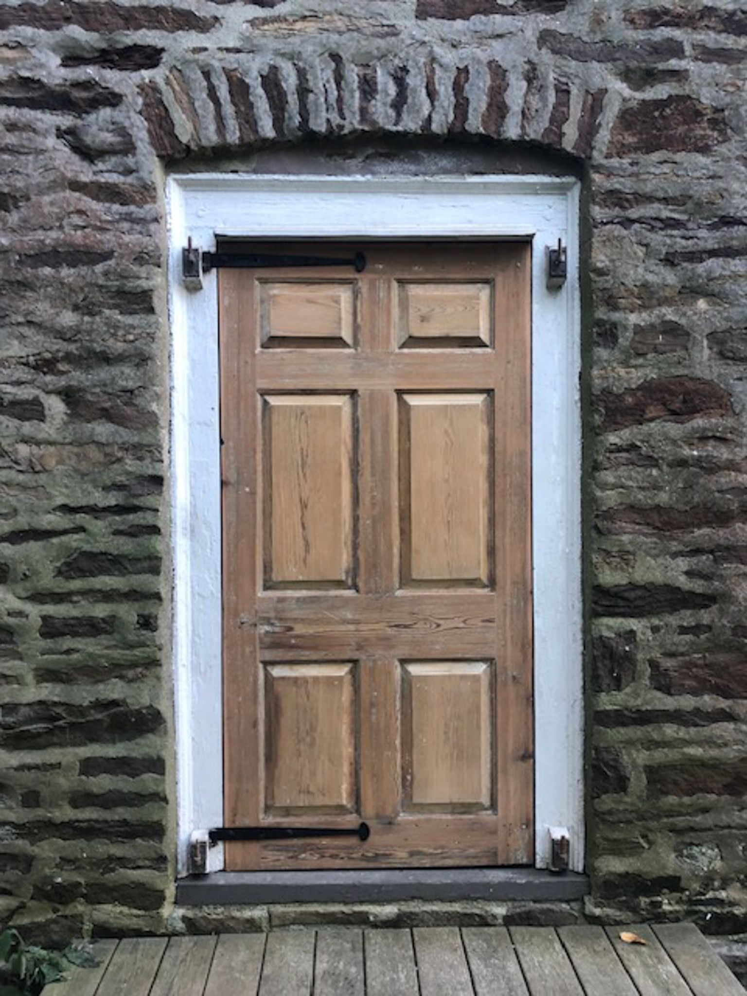 A wooden door is sitting in front of a stone wall.