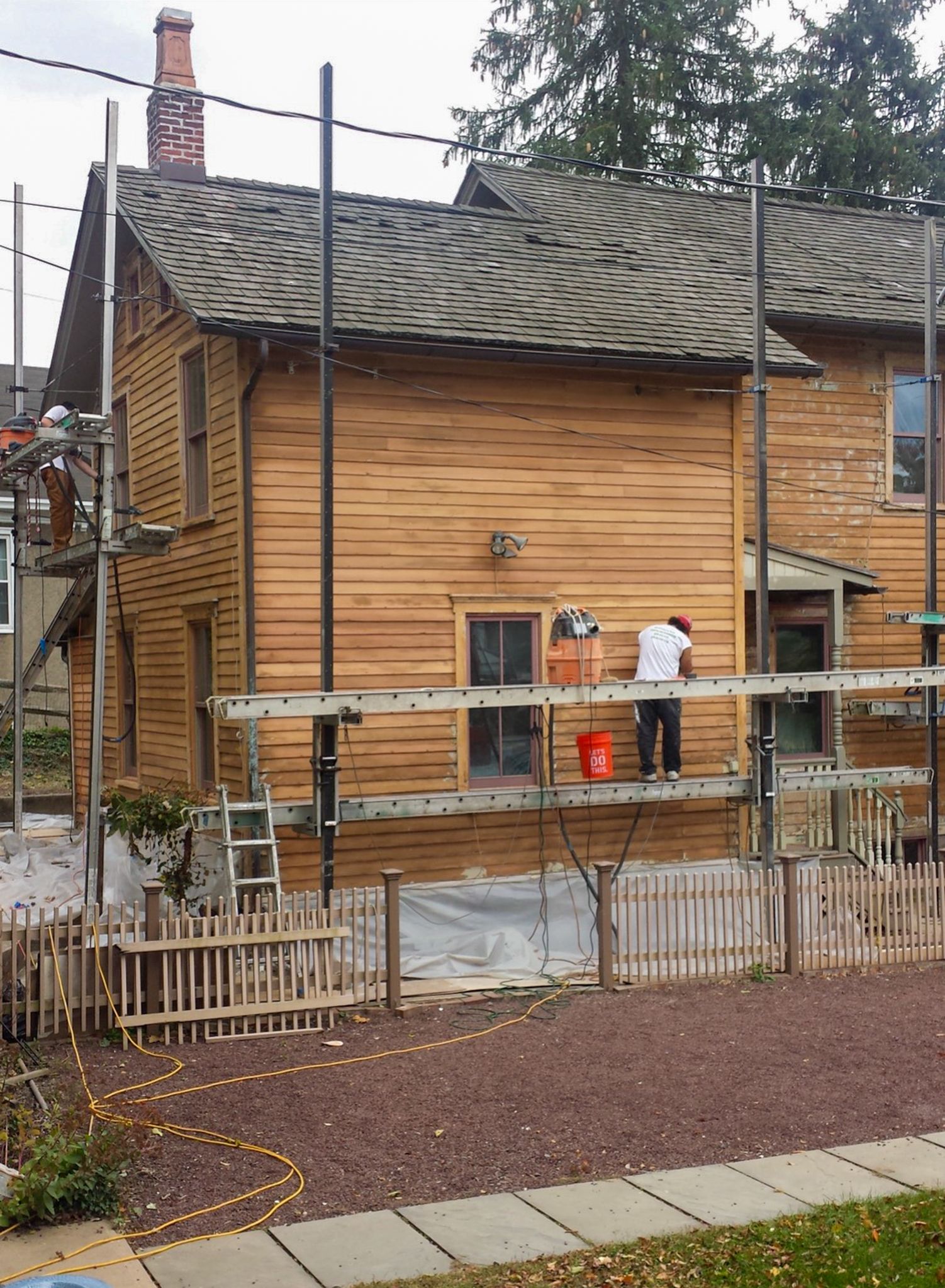 A man is painting the side of a wooden house