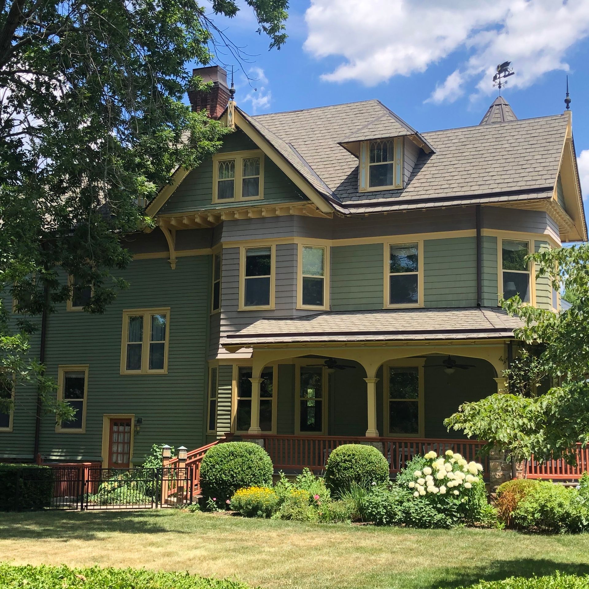 A green house with a gray roof and a porch