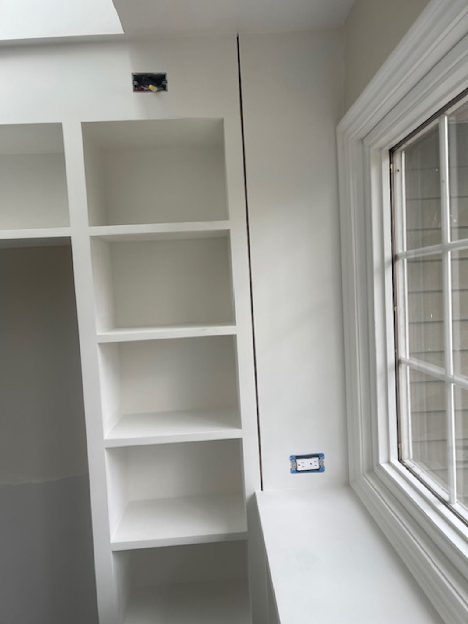 A room with white shelves and a window