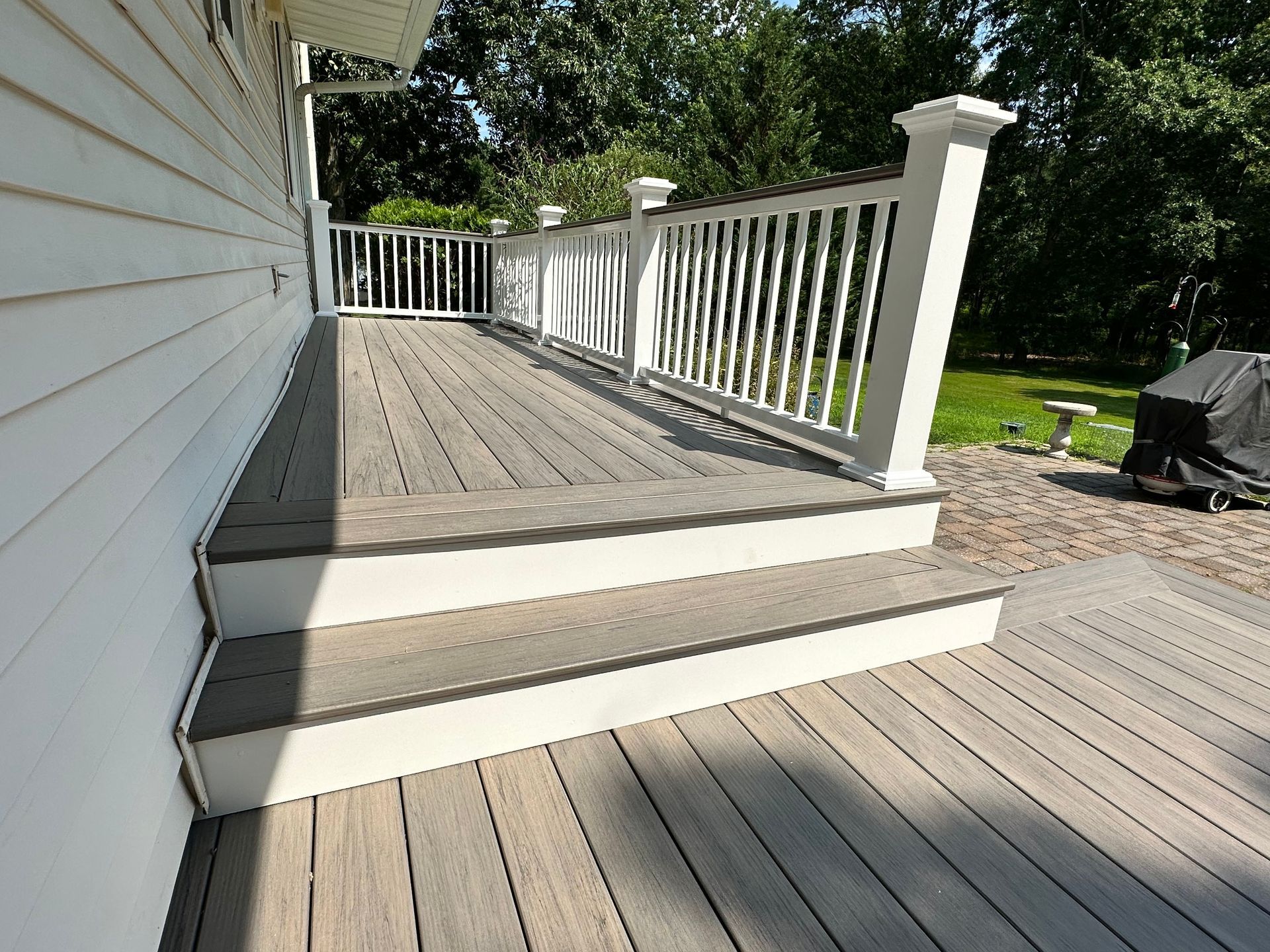 A wooden deck with stairs and a white railing