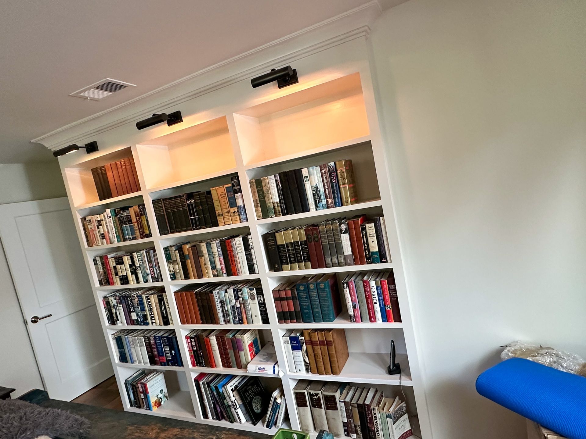 A large white bookshelf filled with books in a living room.
