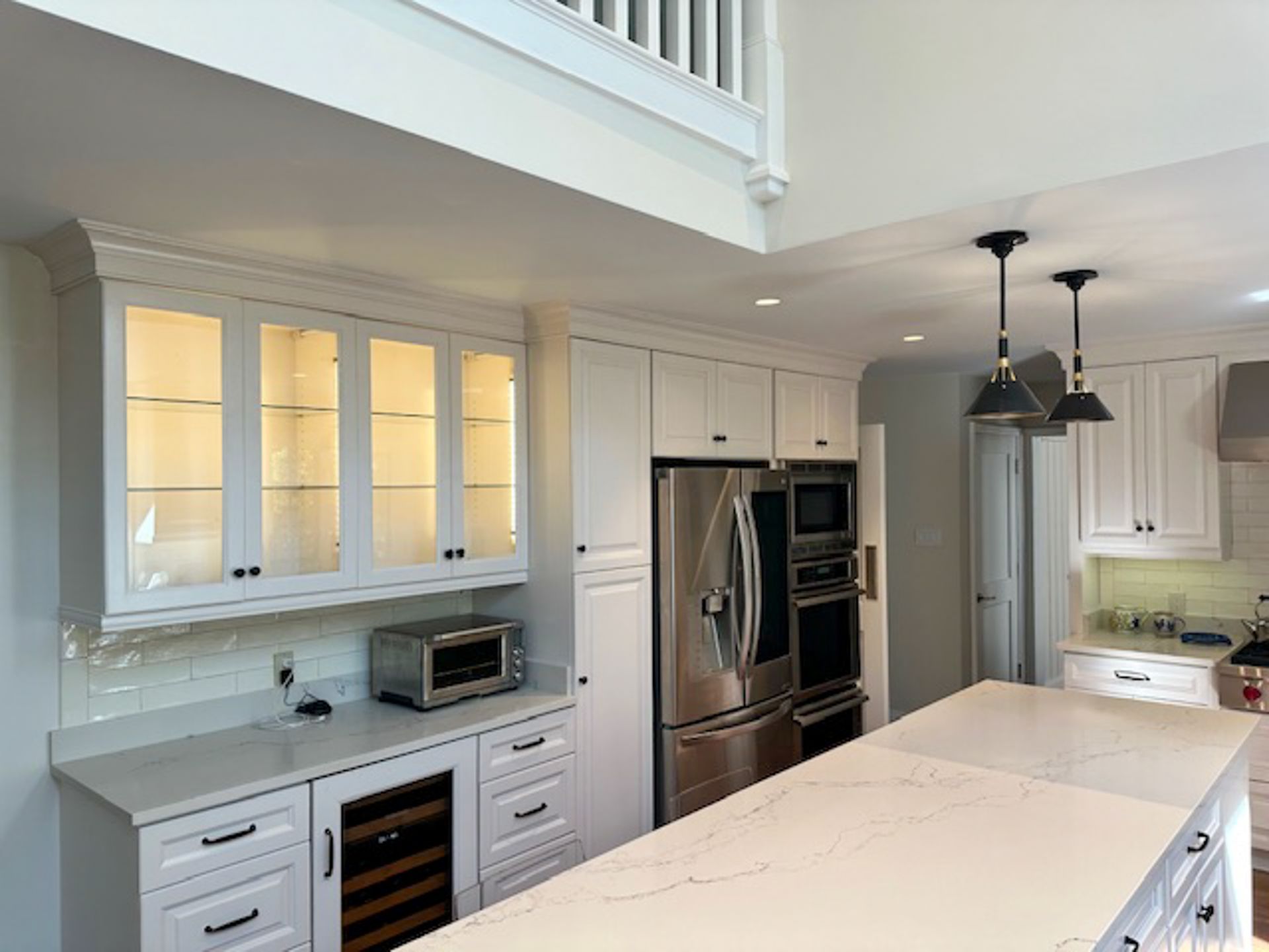 A kitchen with white cabinets , stainless steel appliances , and a large island.