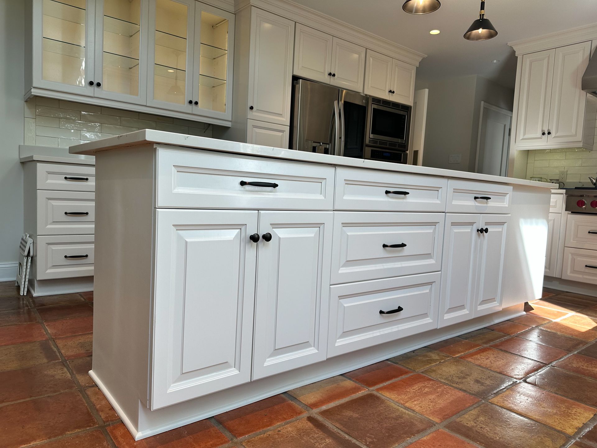 A kitchen with white cabinets and drawers and a large island in the middle.