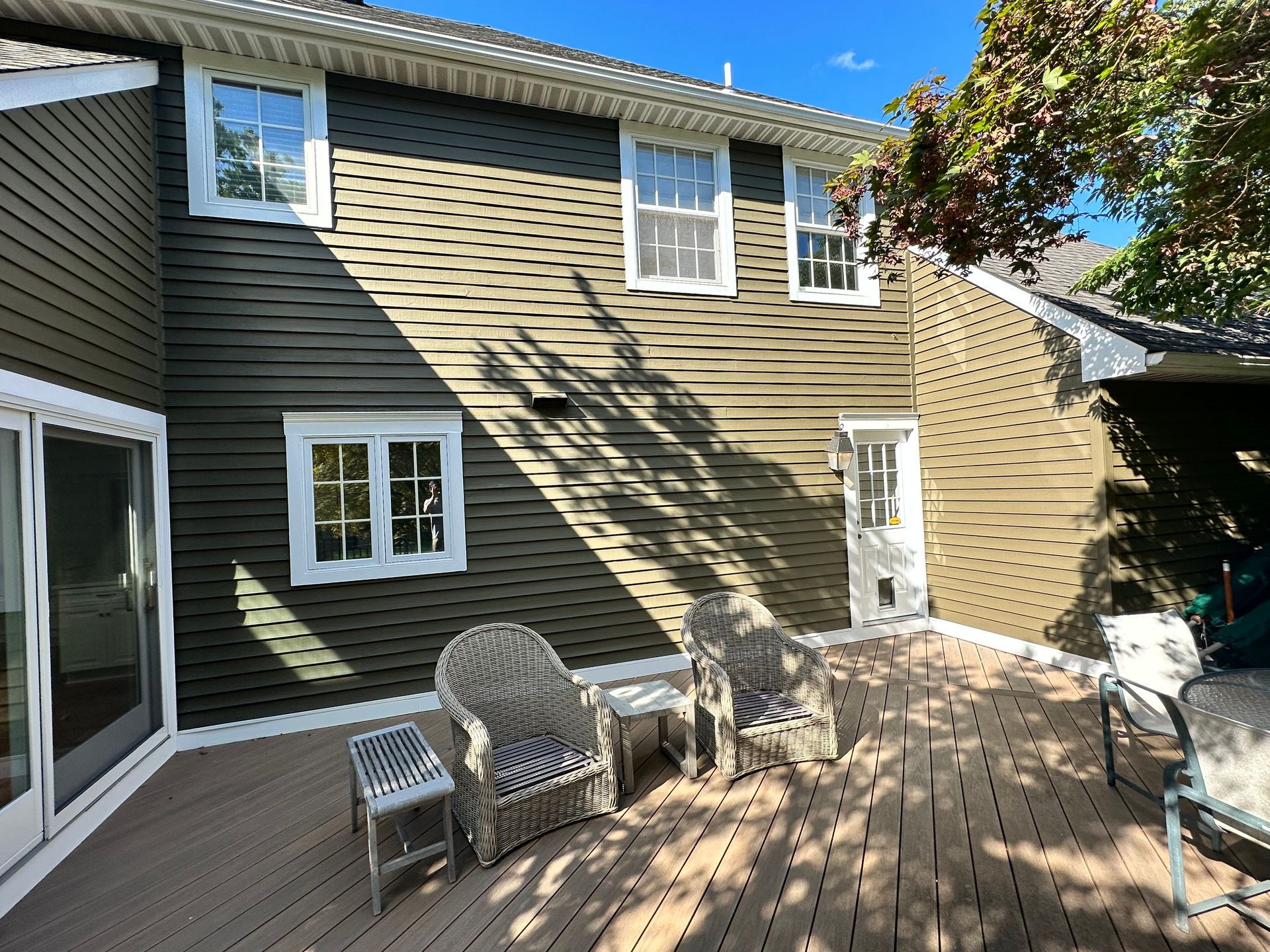 A deck with chairs and a table in front of a house.
