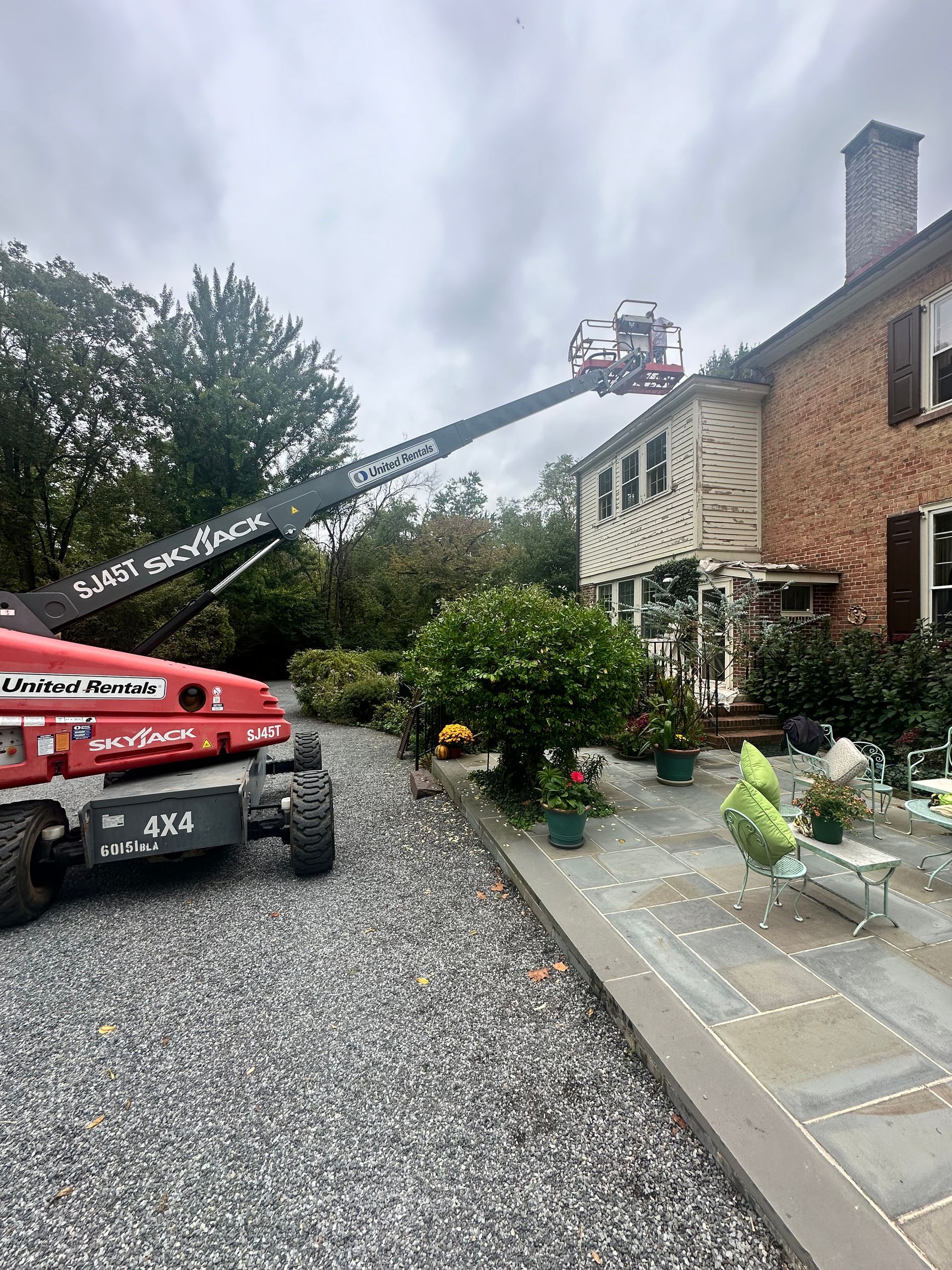 A red crane is sitting in front of a large brick house.