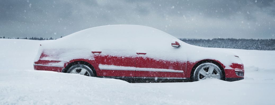 A red car is driving through a snowy field. A red car is driving through a snowy field.