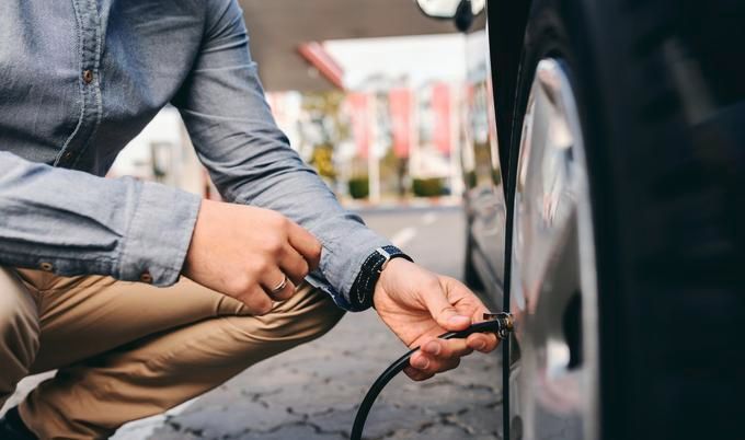 A man is inflating a tire with a hose. A man is inflating a tire with a hose.