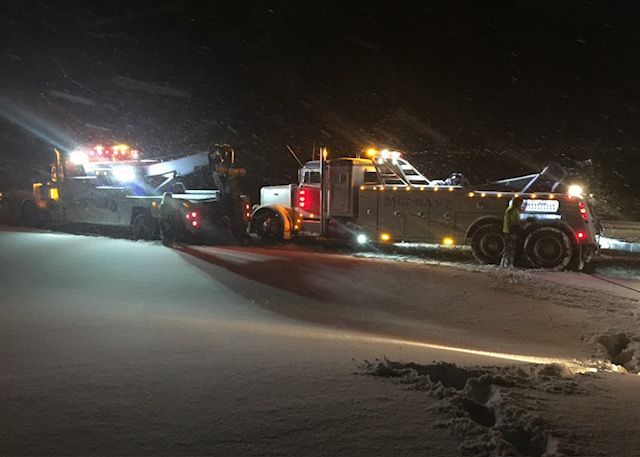 tow truck  on road in snow at night