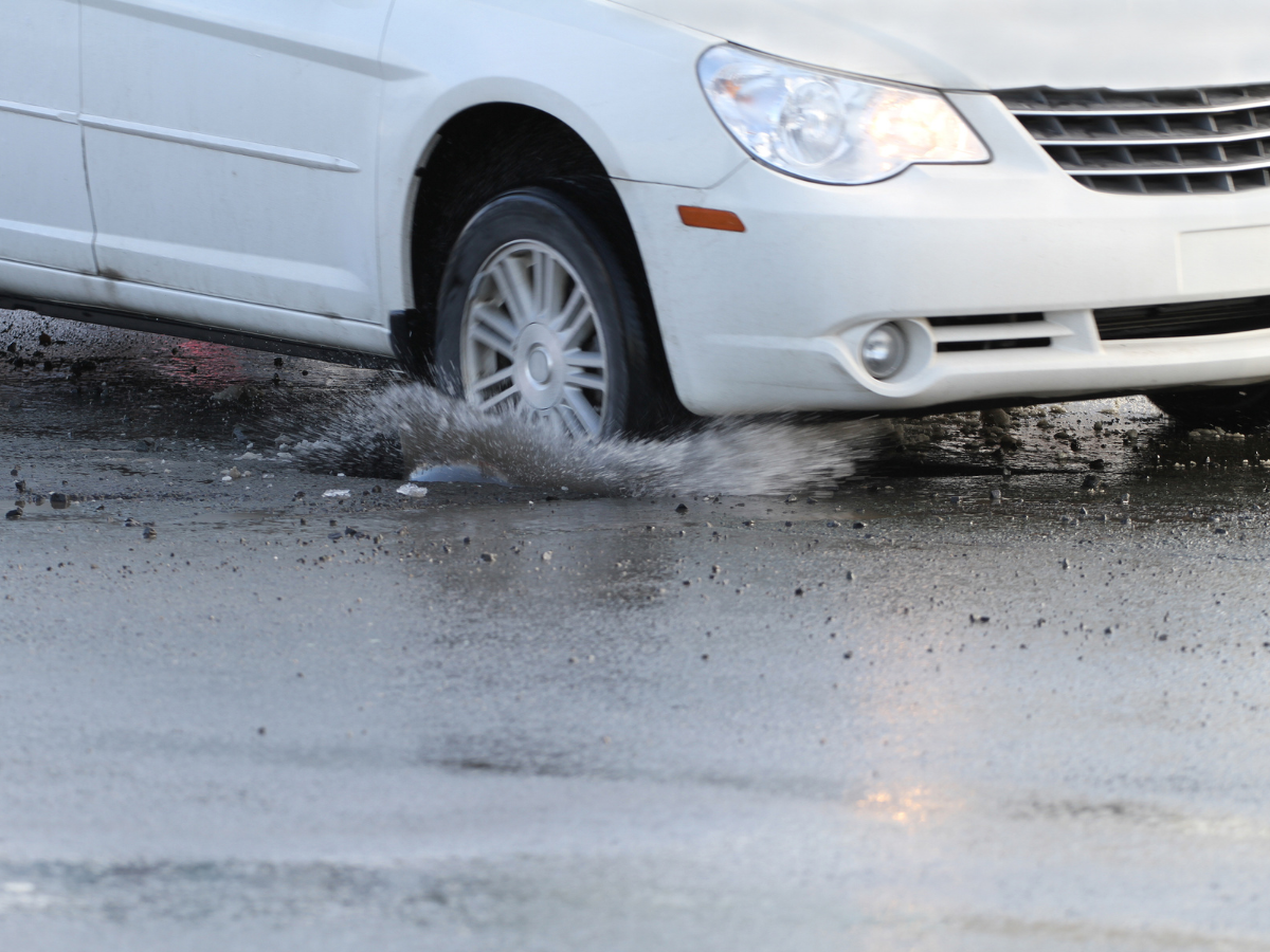 A white car is driving through a puddle of water A white car is driving through a puddle of water