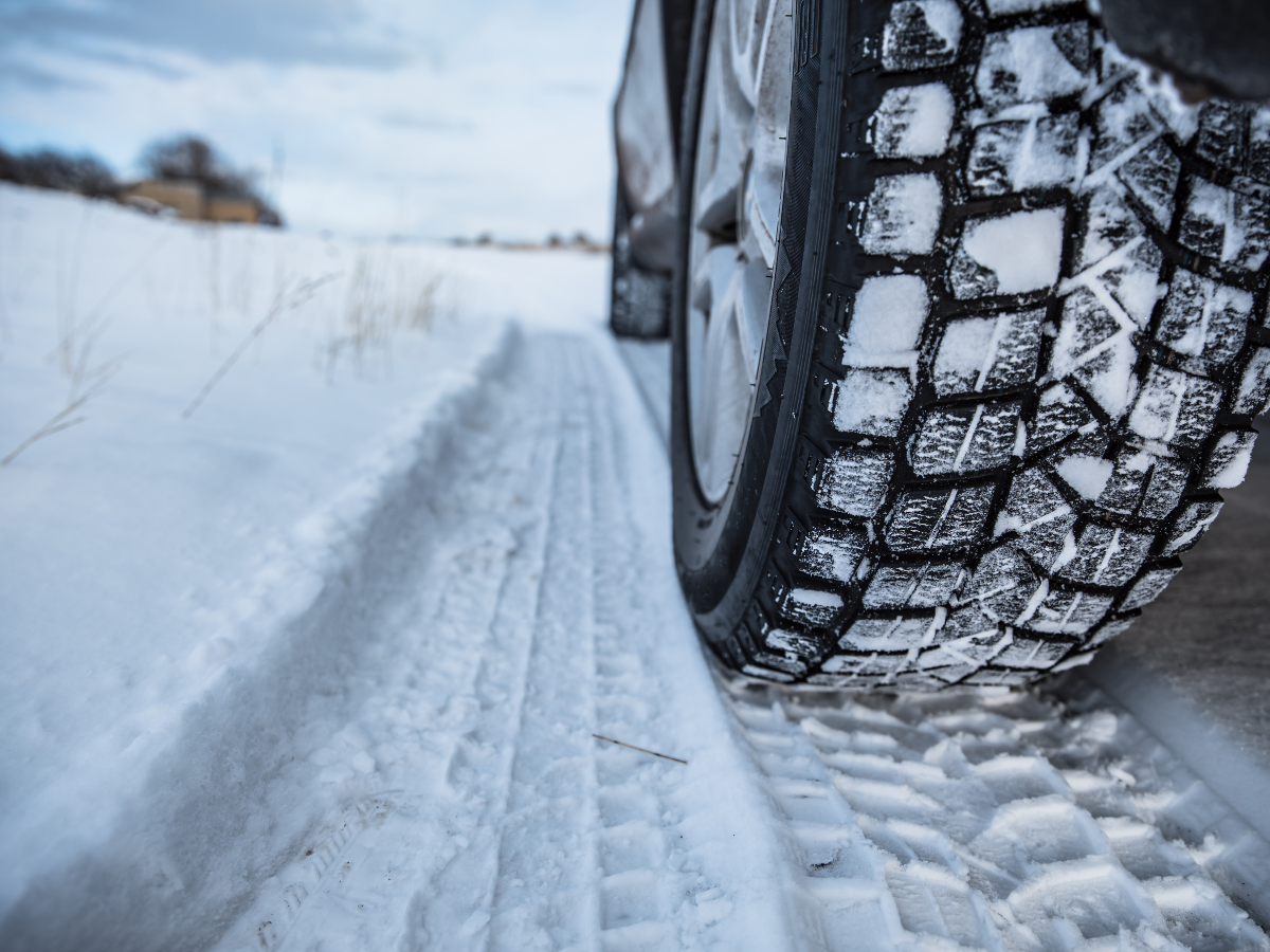 A close up of a car tire on a snowy road. A close up of a car tire on a snowy road.