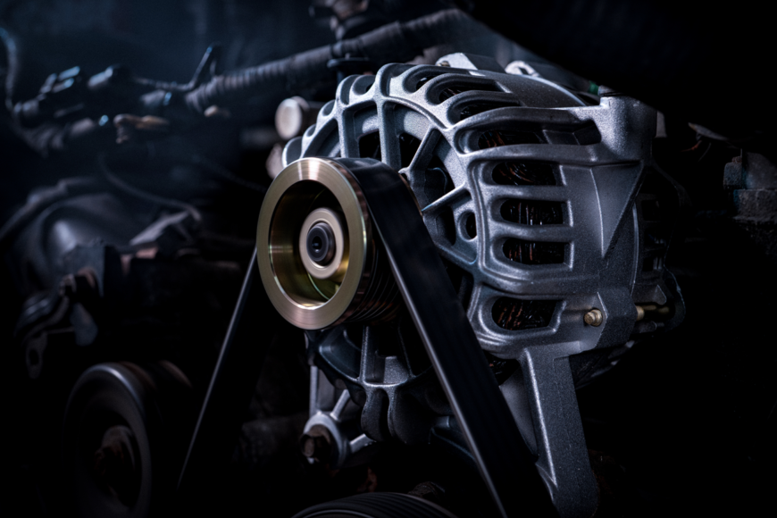 A close up of a car engine with a belt attached to it. A close up of a car engine with a belt attached to it.