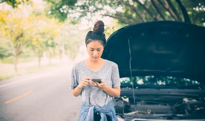 A woman on the side of the highway waiting for her towing service. A woman on the side of the highway waiting for her towing service.