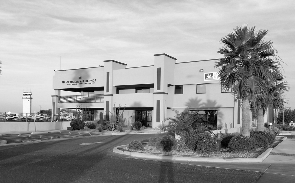 Chandler Air Service - A multi-story building featuring a large balcony, located near an airport control tower.