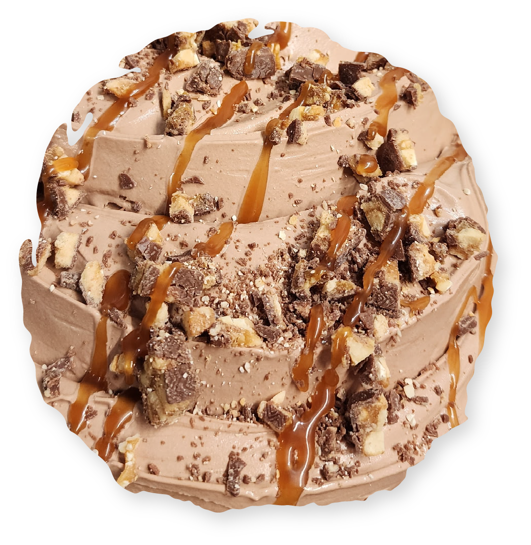 A round chocolate dessert topped with caramel drizzle and chopped nut-filled candy pieces on a white background.