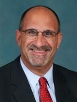 A man in a suit and tie is smiling for the camera.